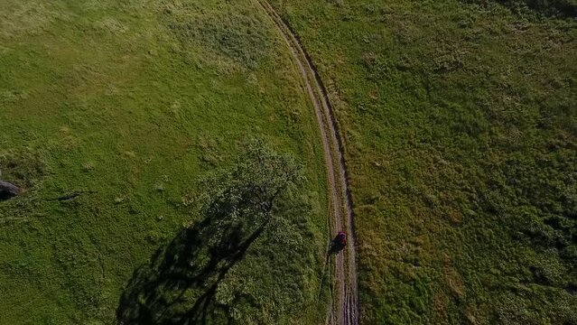 Aerial View of ATV Driving Down Long Dirt Road Speeding Past Trees