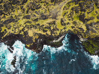 Top down view at a cliff and waves crushing on the rocky volcanic coast on stormy autumn day