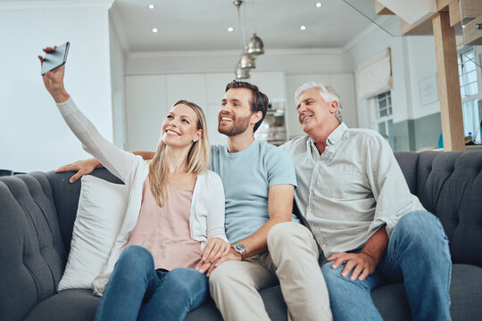 Selfie, phone and happy family on a sofa in the living room relaxing and bonding in their modern home. Happiness, love and young couple taking a picture on a cellphone with a senior man in a lounge.