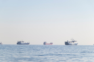 far away harbor cranes sun on the hill a clear blue still sea waves and sky