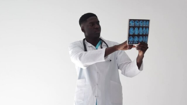 An African specialist doctor studies the patient's EEG condition. Identification of brain deformities. holding a CT scan photo