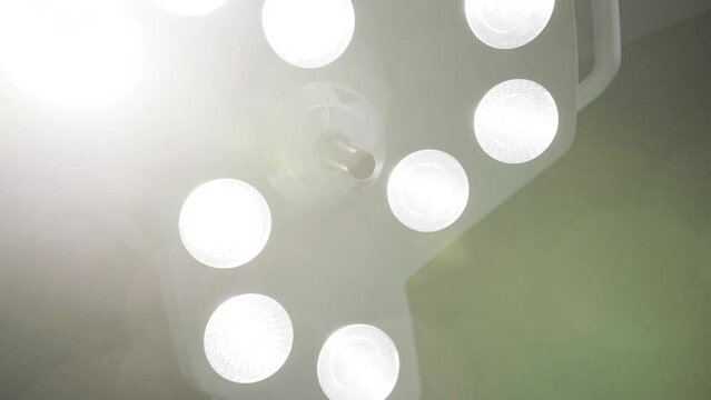 large surgical lamps shine under the ceiling of the operating room, illuminating the surgical field with bright light medical hospital concept 