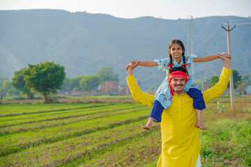 Happy indian farmer with little daughter at agriculture field.