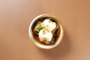 Agedashi is Fried Tofu Served in Warm Dashi Broth and Garnish with grated ginger, chopped scallions and bonito flakes. 