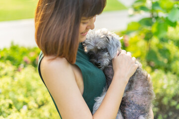 Yong asian woman in casual outfit of cheerful with old dog at outdoors. Young woman playing with her little adopted dog pet and owner having good time together. Hugs and kisses, Love, Care, Friendship