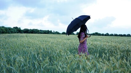 woman back holding an umbrella in a wheat field