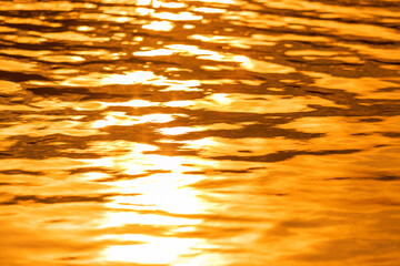 Abstract photo of surface water of sea or ocean at sunset time with golden light tone. and dark shadow.