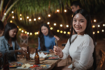 Asian young woman showing off eating steak at a party