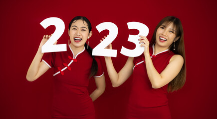 Happy asian women in red traditional chinese dress holding 2023 number for celebrate Chinese New...