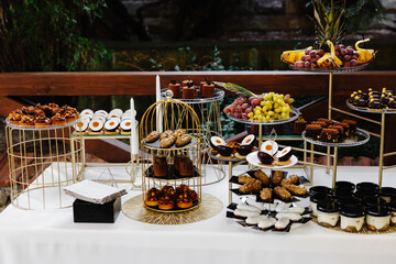Many cakes standing among the candy bar. Sweet table. Banquet table. Holiday food and sweet festive table.