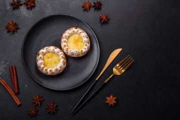 Delicious fruity sweet tart with lemon flavor and cream on a black plate