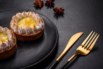 Delicious fruity sweet tart with lemon flavor and cream on a black plate