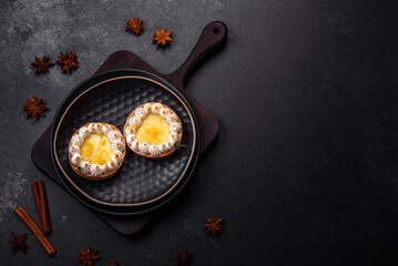 Delicious fruity sweet tart with lemon flavor and cream on a black plate