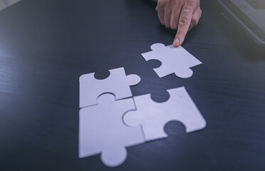 Man's hand putting connect jigsaw puzzle. Teamwork and strategic solution concept. Selected focus	