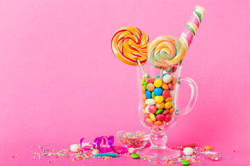 Colorful candies in cup on table on light background background. Large swirled lollipops. Creative...