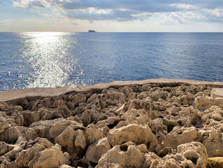 Panoramic view of Filfa island (Malta) with rock shore in the foreground. Artistic photo of little maltese island Filfla during sunset hours. December in Malta