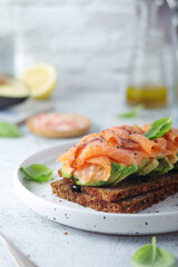A rye bread sandwich with avocado and salmon	