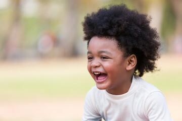 African American boy playing outdoor in the park. Cheerful little boy having fun alone in the garden