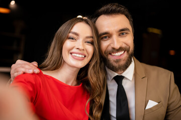portrait of cheerful young couple in festive attire looking at camera