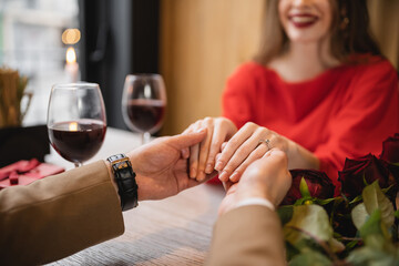 cropped view of happy woman with engagement ring on finger holding hands with man on valentines day