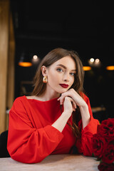 brunette young woman looking at camera near red roses on valentines day