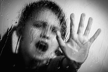 Children violence. Portrait of young girl with her hand extended showing STOP gesture. Selective focus. Black and white image.