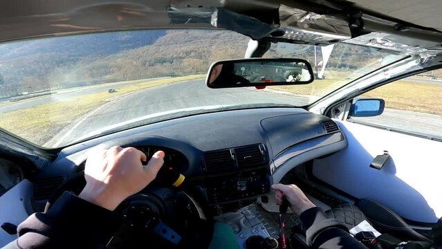 Driver feeling adrenaline while drifting car on sport playground, POV driver inside the car quickly steering wheel and doing dangerous extreme maneuvers in drifting