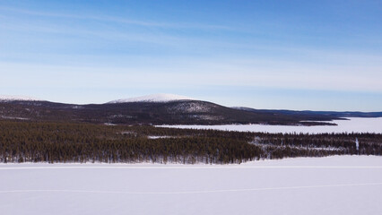 frozen lake with forest and mountain landscape in finnish lapland during winter