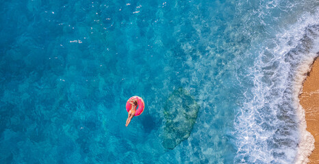 Concept tropical paradise travel relax. Aerial top view young woman swimming with donut pink...