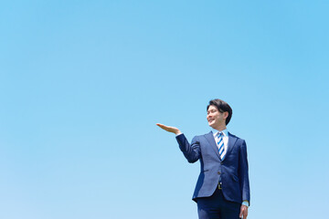 屋外で手のひらで左側を指すビジネスマン