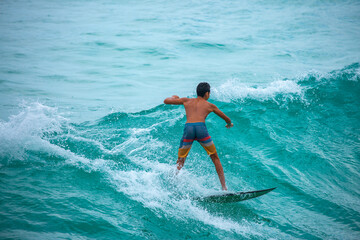 Surfing on a water board. A professional surfer rides the waves in Bali, Indonesia. Male athlete catches waves in the ocean.