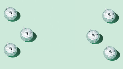 Shiny silver disco balls over green background. Creative Christmas pattern. 90s retro party time concept. Xmas holiday background. Top view. Flat lay. Copy space