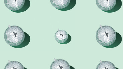 Shiny silver disco balls over green background. Creative Christmas pattern. 90s retro party time concept. Xmas holiday background. Top view. Flat lay.
