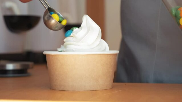Closeup shot of chef hand decorating ice cream with cherry and peanuts. yogurt ice cream with cherries and peanuts