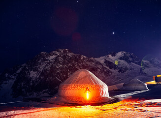 Man with light sword near Yurt nomadic house at night at Mountains
