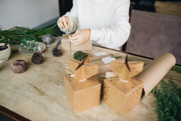 Woman wrapping christmas presents with eco materials at home