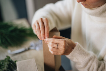Obraz premium Woman wrapping christmas presents with eco materials at home