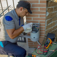 Expert in automatic systems while repairing the electronic card of a gate. Technician repairing and installing the motor of an automatic driveway gate.

