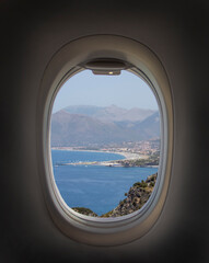Airplane window with beautiful sky. Airplane window. View of the sea, mountains and clouds. Travel and tourism concept. New scenic spots