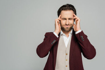 tired showman in formal wear suffering from headache isolated on grey