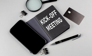 KICK -OFF MEETING text written on black notebook with smartphone, magnifier and credit card