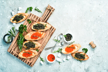 Sandwiches with caviar and butter. Caviar in a bowl. Premium snacks. On a stone background. top view