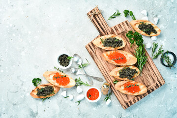 Set of sandwiches with red and black caviar and butter. Caviar in a bowl. Premium snacks. On a stone background. top view