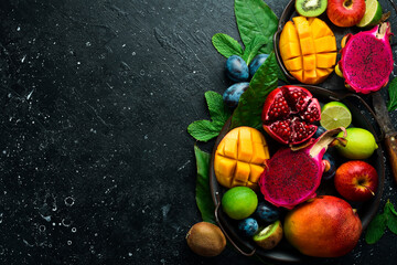 Background of exotic fruits. Ripe tropical fruits on a stone background. Copy space. Top view.