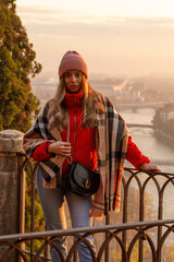 Young girl with rose hat checkered scarf red jacket black bag enjoying the picturesque view to...