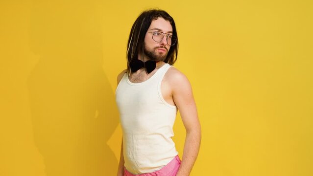 Portrait Of A Young Transgender Man Dressed In A White T-shirt, Pink Pants And Bow Tie On A Yellow Background