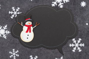 Blank talk bubble chalk sign with a snowman on snowflake fabric