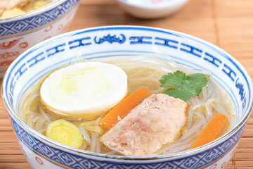 Close-up of rice noodle soup and pork meat.