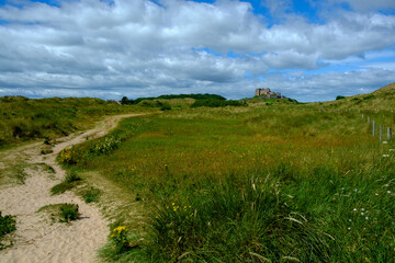 Historic Bamburgh Castle glimpsed in the distance from the dunes behind Bamburgh beach, Northumberland, UK