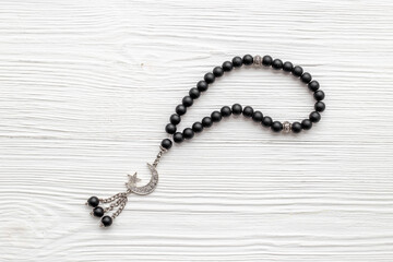 Black Muslim rosary with silver crescent moon. Islamic background